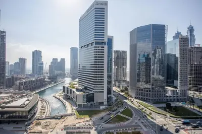 a tall building in a large city with a river at Waterfront 1 BR - Canal View - Fully Furnished - Business Bay - 15 Mins to Dubai Mall and Burj Khalifa in Dubai