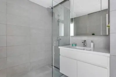 a white bathroom with a sink and a shower at Waterfront 1 BR - Canal View - Fully Furnished - Business Bay - 15 Mins to Dubai Mall and Burj Khalifa in Dubai