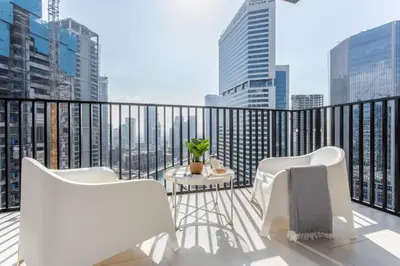 a balcony with white chairs and a view of the city at Waterfront 1 BR - Canal View - Fully Furnished - Business Bay - 15 Mins to Dubai Mall and Burj Khalifa in Dubai