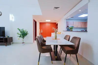 a dining room with a table and chairs at Best Deal I Spacious Apartment I Full Amenities including Balcony, Pool, Gym, Kids Play Area in Dubai