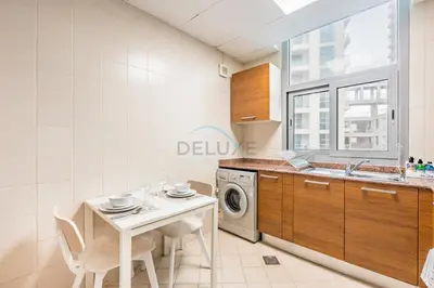a kitchen with a table and a washing machine at Studio Steps from JBR Beach and Marina Walk, Conveniently located near Ain Dubai, Dec Towers T2, Dubai Marina by Deluxe Holiday Homes in Dubai