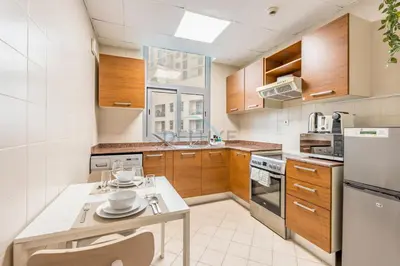 a kitchen with wooden cabinets and a table with dishes on it at Studio Steps from JBR Beach and Marina Walk, Conveniently located near Ain Dubai, Dec Towers T2, Dubai Marina by Deluxe Holiday Homes in Dubai