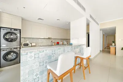 a kitchen with two chairs and a washing machine at FIRST CLASS 2BR Timeless Vibes & Pool View in Dubai