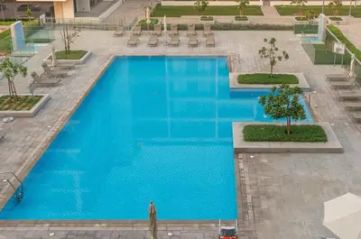 a large blue swimming pool with chairs and trees at FIRST CLASS 2BR Timeless Vibes & Pool View in Dubai