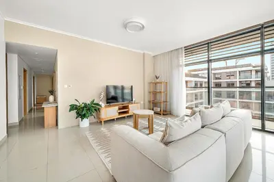 a living room with a white couch and a tv at FIRST CLASS 2BR Timeless Vibes & Pool View in Dubai