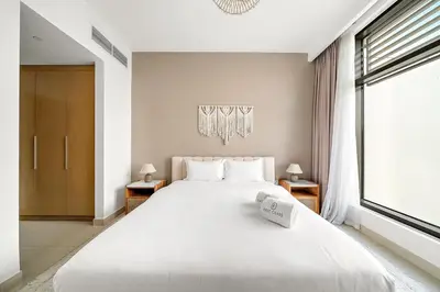 a bedroom with a large white bed and a window at FIRST CLASS 2BR Timeless Vibes & Pool View in Dubai