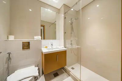 a bathroom with a shower and a sink and a mirror at FIRST CLASS 2BR Timeless Vibes & Pool View in Dubai