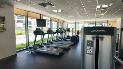 a gym with a row of treadmills in a room at FIRST CLASS 2BR Timeless Vibes & Pool View in Dubai