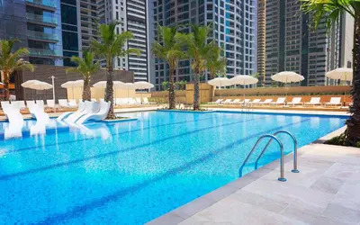 a large swimming pool with white chairs and umbrellas at Design 1br Apartment with Dubai Marina View in Marina Gate 2 in Dubai
