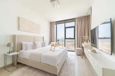 a white bedroom with a bed and a large window at Frank Porter - Bloom Tower C in Dubai