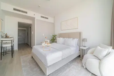 a white bedroom with a white bed and a couch at Frank Porter - Bloom Tower C in Dubai