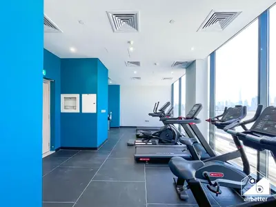 a gym with cardio machines and blue walls at Elegant 1BR at Azizi Riviera l Prime Location in Dubai
