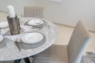 a dining room table with white plates and chairs at Stylish 1BR DunyaTower Apartment 2min to DubaiMall in Dubai