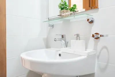 a white bathroom with a sink and a mirror at Stylish 1BR DunyaTower Apartment 2min to DubaiMall in Dubai