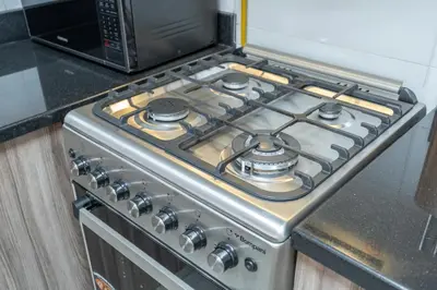 a stove top oven in a kitchen next to a microwave at Stylish 1BR DunyaTower Apartment 2min to DubaiMall in Dubai
