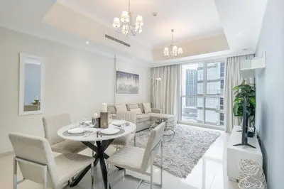 a white living room with a table and chairs at Stylish 1BR DunyaTower Apartment 2min to DubaiMall in Dubai