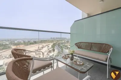 a balcony with a table and chairs and a view at Vogue Damac Hills Golf Gate near First Avenue Mall, Two Bedroom Apartment with Balcony and Vibrant Community View, Access to all Amenities in Dubai