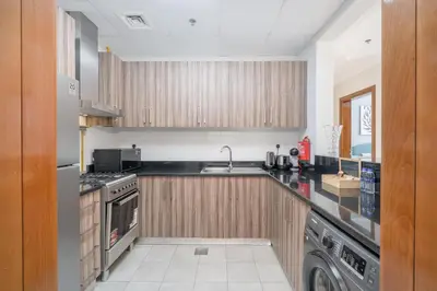 a kitchen with wooden cabinets and a sink and a dishwasher at Luxury Apartment l 2 min walk from Dubai Mall in Dubai