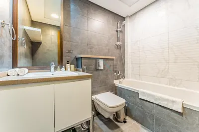 a bathroom with a toilet and a sink and a tub at Few Metres Walk to Metro, Minutes Drive from Ibn Battuta Mall, Victoria Residency, Al Furjan by Deluxe Holiday Homes in Dubai