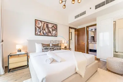 a white bedroom with a large bed and a table at Few Metres Walk to Metro, Minutes Drive from Ibn Battuta Mall, Victoria Residency, Al Furjan by Deluxe Holiday Homes in Dubai