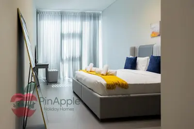 a bedroom with a bed with a yellow blanket at Beautiful Brand New Spacious 1BR in Dubai