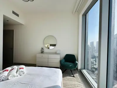 a bedroom with a bed and a chair and a window at Homelike Charm High-End Furnished and Luxurious in Dubai