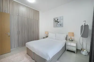 a white bedroom with a bed and a television at EasyGo-Elavated Urban Living Stylish 3Bedroom townhouse in Dubai