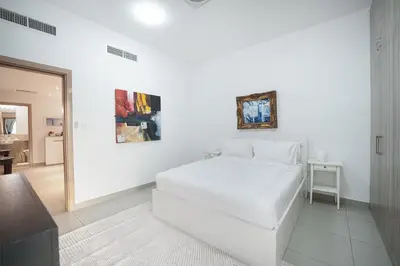 a white bedroom with a white bed and a mirror at EasyGo-Elavated Urban Living Stylish 3Bedroom townhouse in Dubai