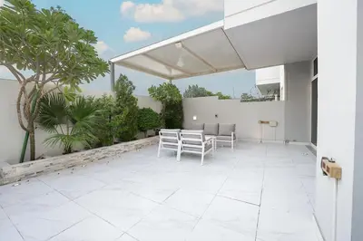 a patio with a table and chairs on a building at EasyGo-Elavated Urban Living Stylish 3Bedroom townhouse in Dubai