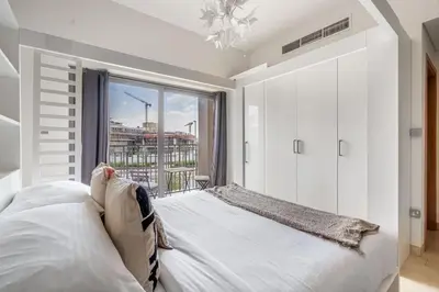 a white bedroom with a bed and a large window at Luxury Studio Apartment in Dubai
