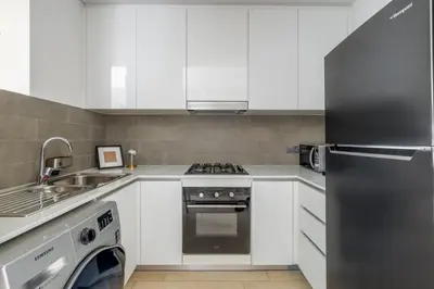 a kitchen with white cabinets and a stove top oven at Luxury Studio Apartment in Dubai