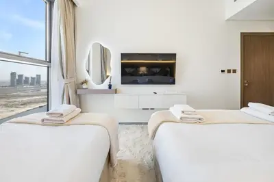 two beds in a white room with a tv at Appealing 2BR at 17 Icon Bay, Dubai Creek Harbour in Dubai
