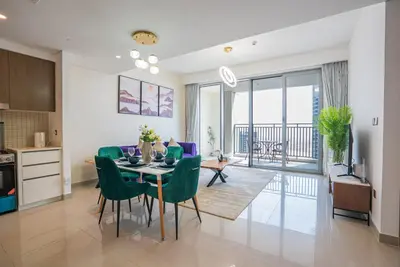 a kitchen and dining room with a table and green chairs at Appealing 1BR at 17 Icon Bay, Dubai Creek Harbour in Dubai