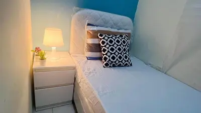 a bedroom with a bed with a lamp and pillows at The Pod Partition Room Al Barsha 1 in Dubai