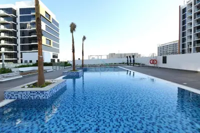 a large blue swimming pool with palm trees and buildings at Modern Studio Near Downtown Dubai, Few Mins Walk to Hartland Greens Park, Azizi Riviera 43, Al Merkadh by Deluxe Holiday Homes in Dubai