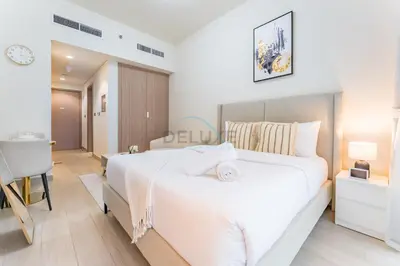 a bedroom with a large white bed and a desk at Modern Studio Near Downtown Dubai, Few Mins Walk to Hartland Greens Park, Azizi Riviera 43, Al Merkadh by Deluxe Holiday Homes in Dubai