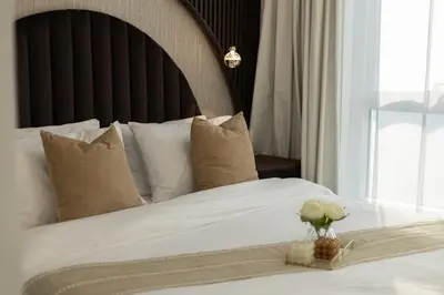 a white bed with a vase of flowers on it at Luxury 2BHK in Jumeirah Lakes Towers Icon 3502 in Dubai