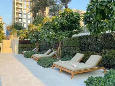 three lounge chairs and trees in a garden at FIRST CLASS 2BR Creek Beach Relax in Style in Dubai
