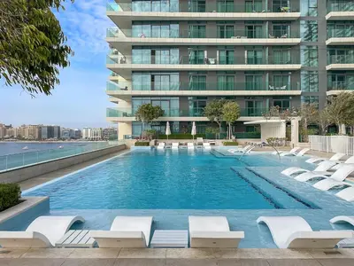 a swimming pool with lounge chairs and a building at FIRST CLASS 2BR Sea & Palm View, Beachfront in Dubai