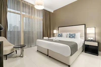 a hotel room with a large bed and a chair at Modern JVC Studio with Pool Gym and Easy Access to Attractions in Dubai