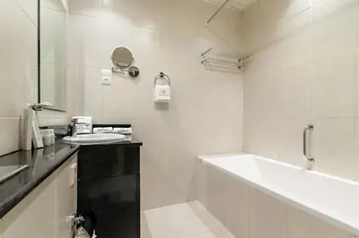 a white bathroom with a tub and a sink at Modern JVC Studio with Pool Gym and Easy Access to Attractions in Dubai