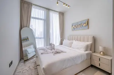 a bedroom with a white bed with a stuffed animal on it at Homes & Beyond l Serene 1BR Retreat in JVC in Dubai