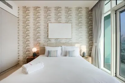 a bedroom with a white bed and a large window at Elegant 2BR with Dubai Marina Skyline & Sunset Views in Dubai