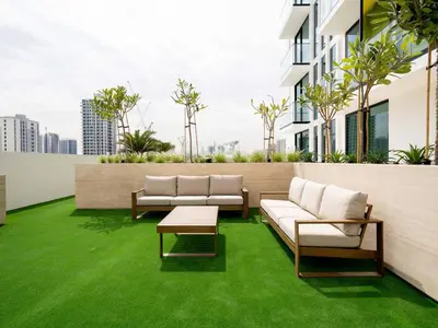 a patio with green grass and couches on a building at Crisp And Curated 1br With Pool, Gym And Parking! in Dubai