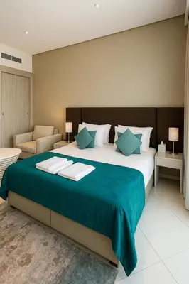 a bedroom with a large bed and a chair at Happy Dom Palm in Dubai
