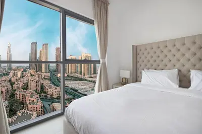 a bedroom with a white bed and a large window at Luxury 2,5BR Burj Khalifa Views with Pool and Gym Access Near Dubai Mall in Dubai