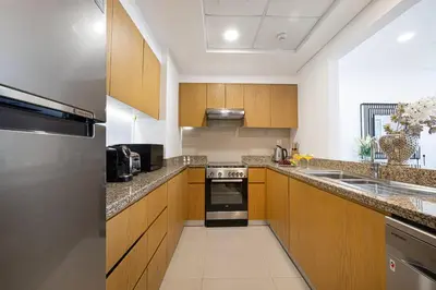 a kitchen with wooden cabinets and a stove top oven at Luxury 2,5BR Burj Khalifa Views with Pool and Gym Access Near Dubai Mall in Dubai
