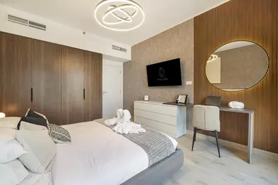 a bedroom with a bed and a desk and a mirror at Elegant Stay with Pool & Gym Near Iconic Landmarks in Dubai