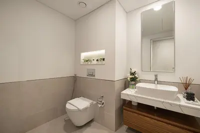 a bathroom with a toilet and a sink and a mirror at Elegant Stay with Pool & Gym Near Iconic Landmarks in Dubai