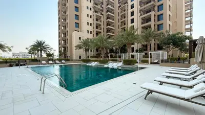 a swimming pool with lounge chairs and a building at Elegant Stay with Pool & Gym Near Iconic Landmarks in Dubai